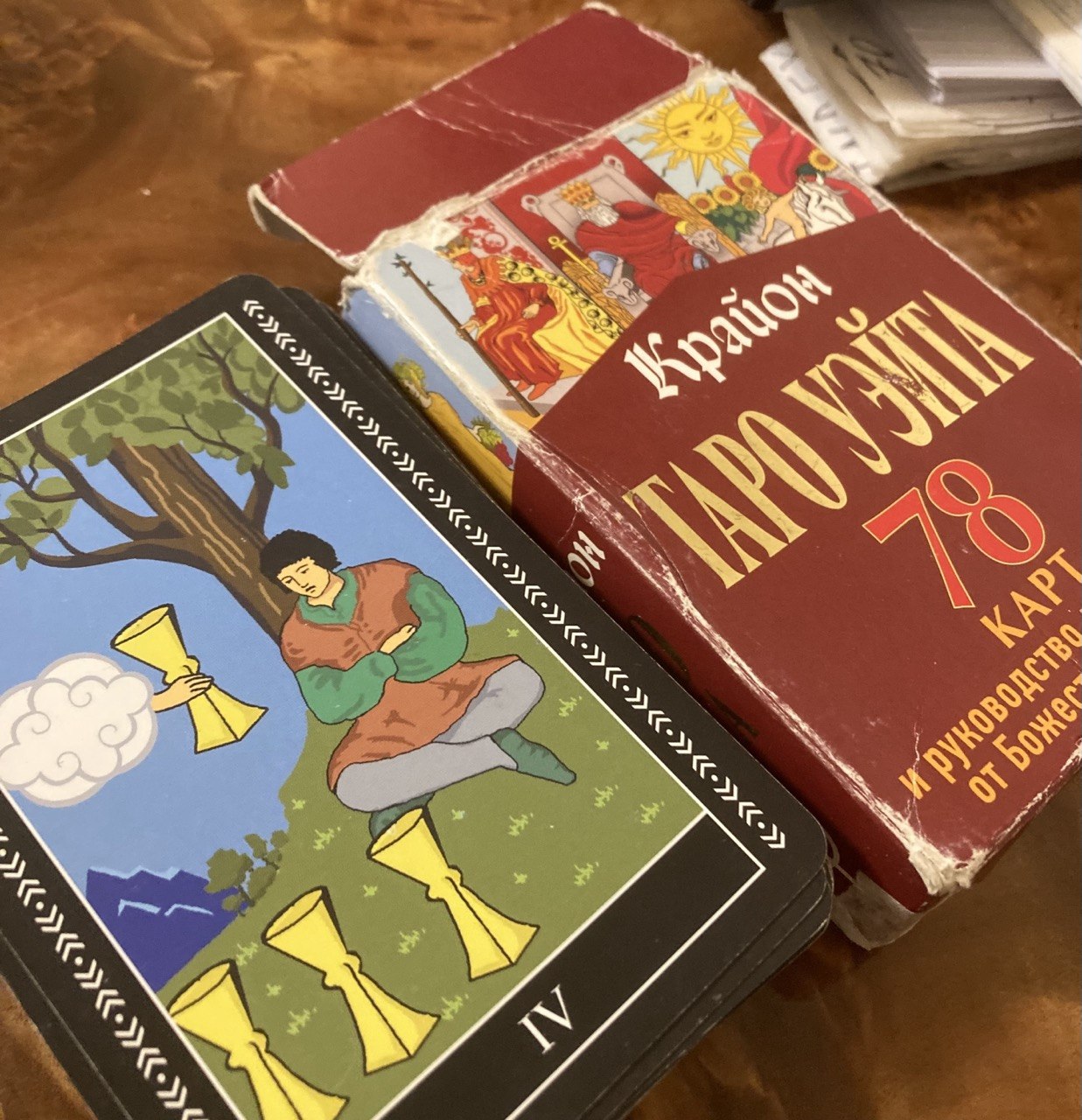 Photo of a Tarot deck and its box. The box says “Крайон / Таро Уэйта: 78 карт и руководство для гадания от Божественного Духа” (Krayon / Waite Tarot: 78 cards and Divine Spirit divination recommendations)